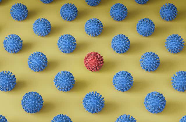 One red 3D-printed virus particle among many blue particles. 