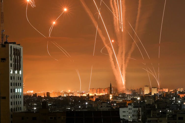 Bright trails of rockets fired towards Israel from the Gaza strip, lighting up the orange night sky