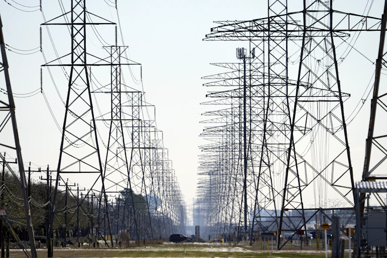 electrical grid transmission line towers recede into a distant landscape