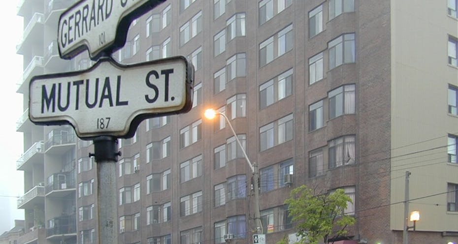 'Mutual St.' streetsign against a tall apartment