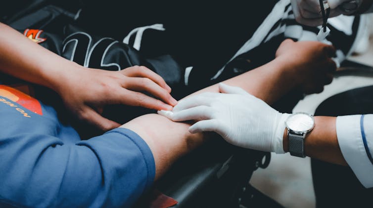 A person applying pressure to their arm where blood was taken.