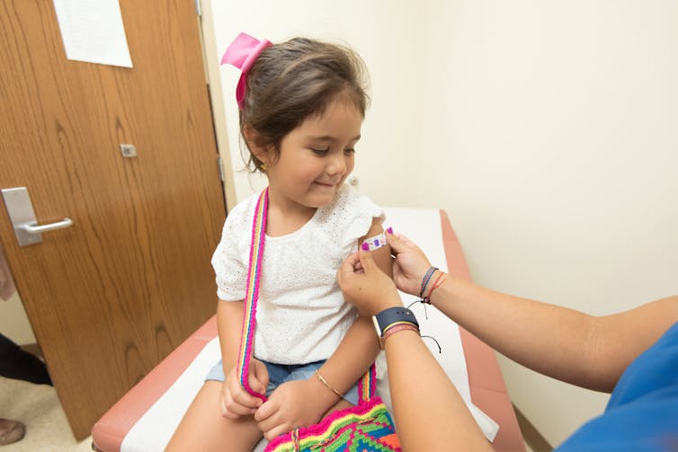 A young girl has a bandaid placed on her upper arm.