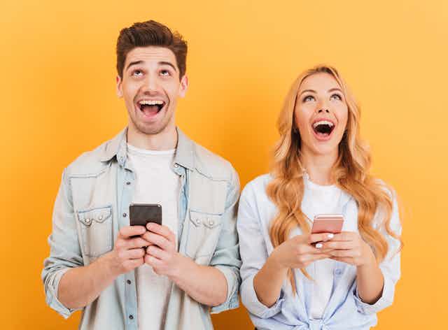 A man and a women looking excited holding phones