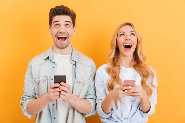 A man and a women looking excited holding phones