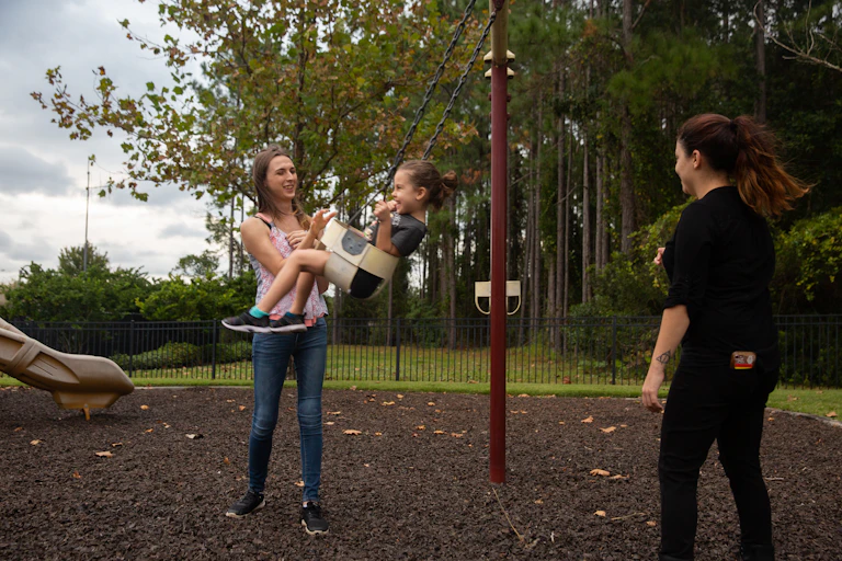 Trans mom and her wife push their child on a swing