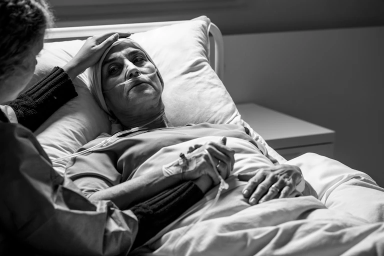 Person dying in hospital bed, holding daughters hand