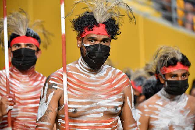 Indigenous performers wearing protective face masks.