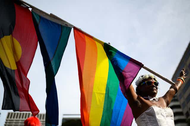A participant waves a flag ahead of the 42nd annual Gay and Lesbian Mardi Gras parade.