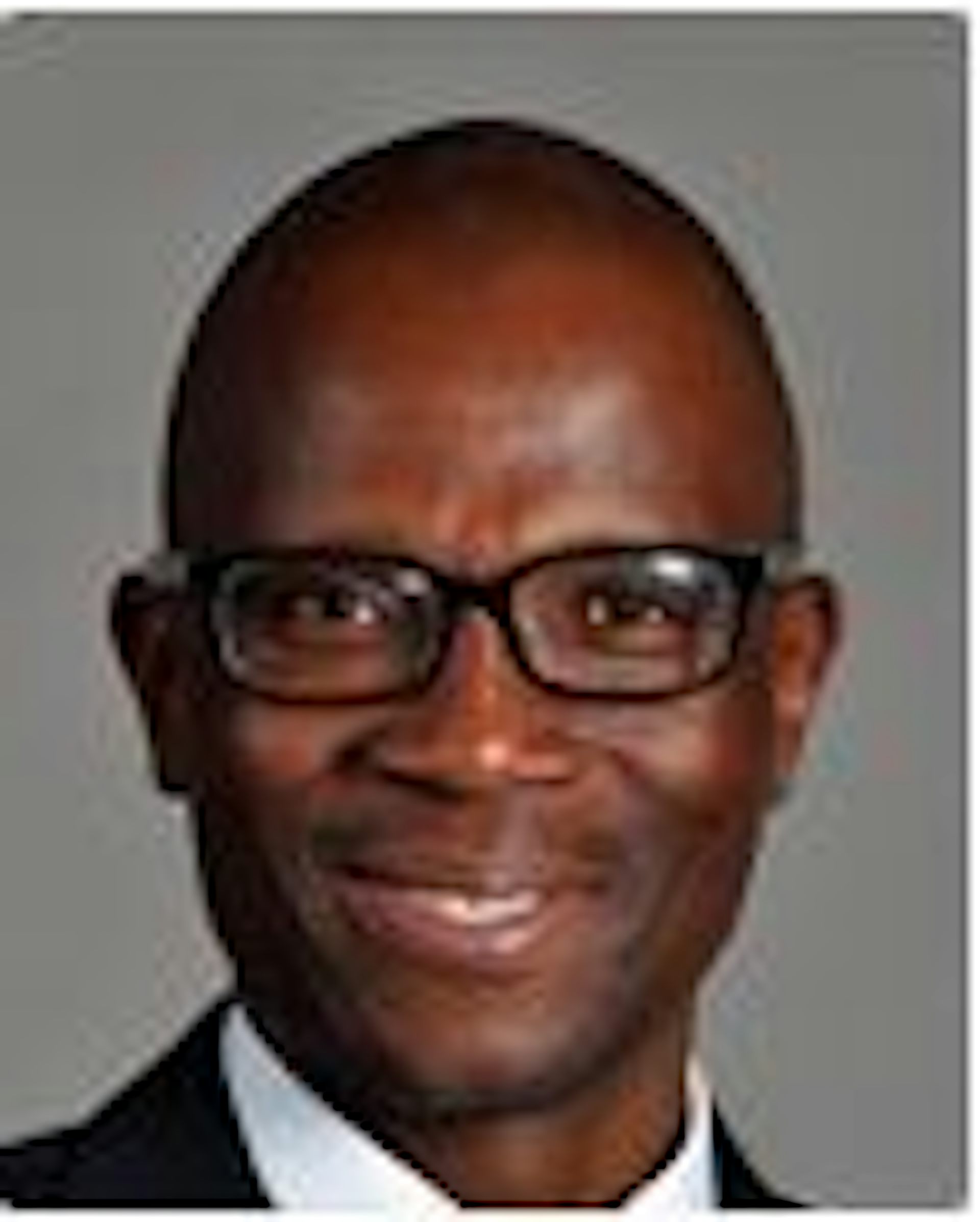 A bespetacled man with a clean shave smiles