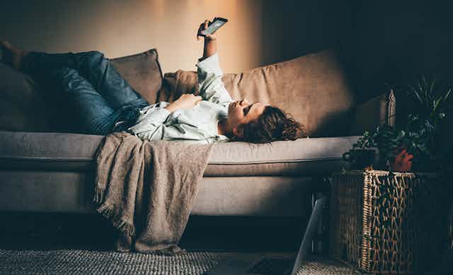 A woman lying on a sofa looking at her phone.
