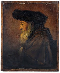 The painted profile of an elder man with a long grey beard, hat and cloak.