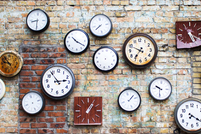 A brick wall with lots of clocks hanging up.