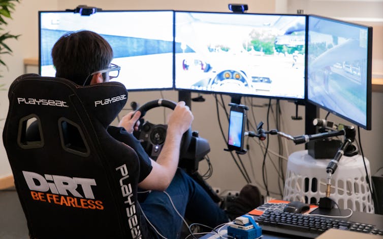 A person sits in a driving simulator