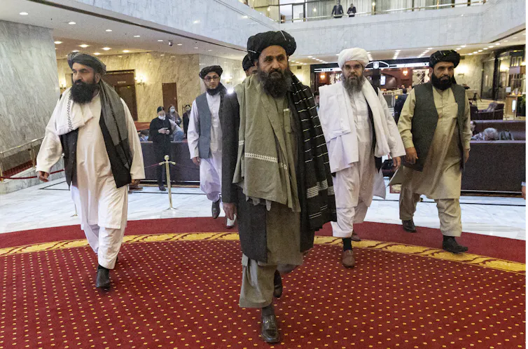 Taliban leaders walk though a lobby.