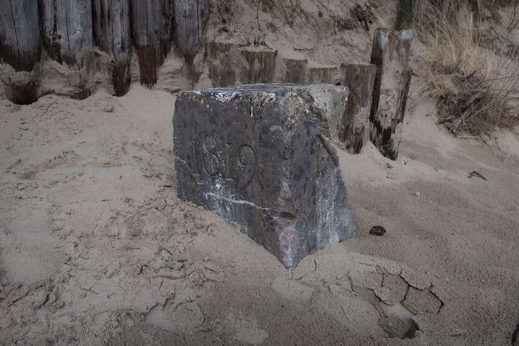 A border stone half buried in sand.