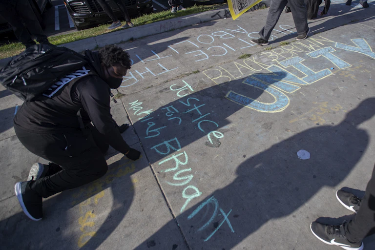 A demonstrator writes a message in chalk on the ground.