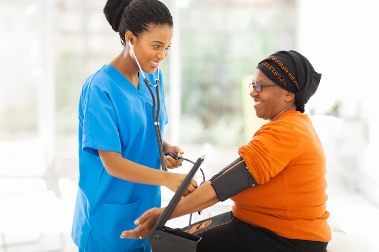 A Black female health professional taking a Black woman's blood pressure.