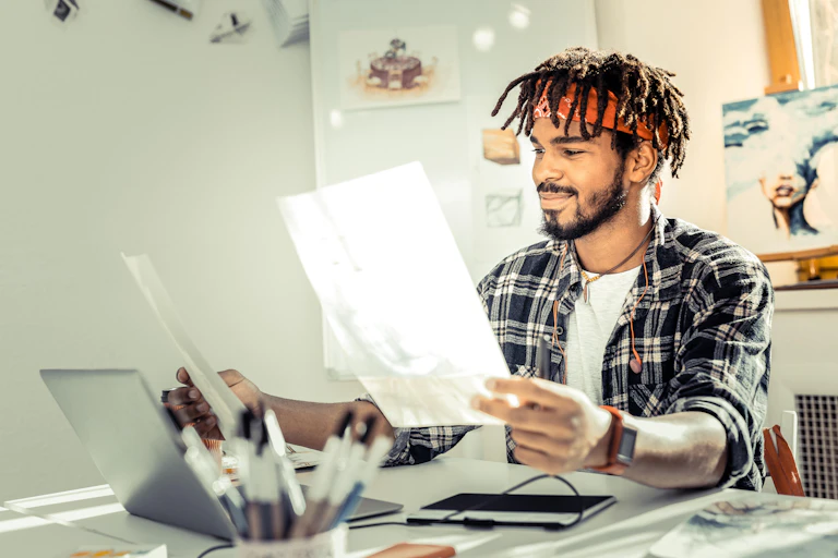 Man sat at desk looks at artwork