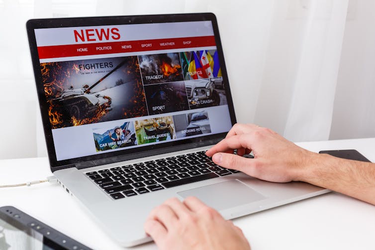 Un homme travaille devant un écran affichant un site de nouvelles