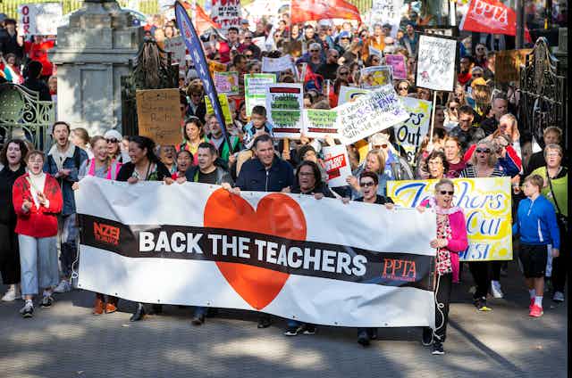 teachers protesting for more pay holding banners