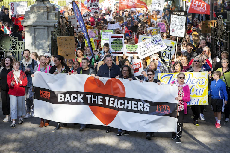 teachers protesting for more pay holding banners