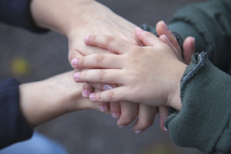 Mother and child place their hands atop each other's