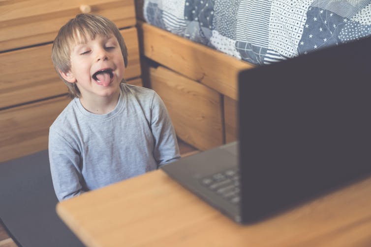 A young boy does a speech therapy session online in front of a laptop