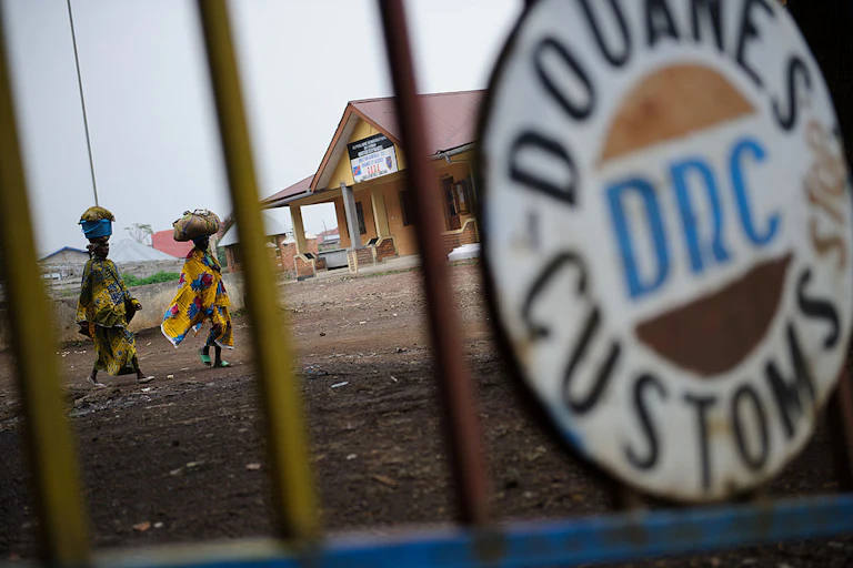 Two women with loads on their heads approach the Congo-Uganda border crossing