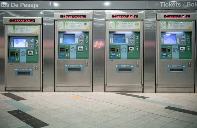 Four gleaming, clean and unused ticket-vending machines in a subway station