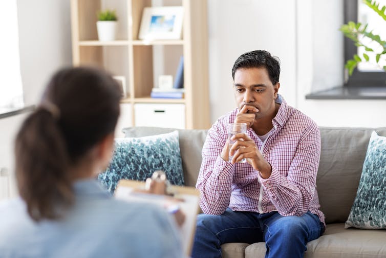 A man sits on the couch during a therapy session.