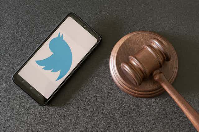 A phone showing the Twitter logo next to a judge's hammer