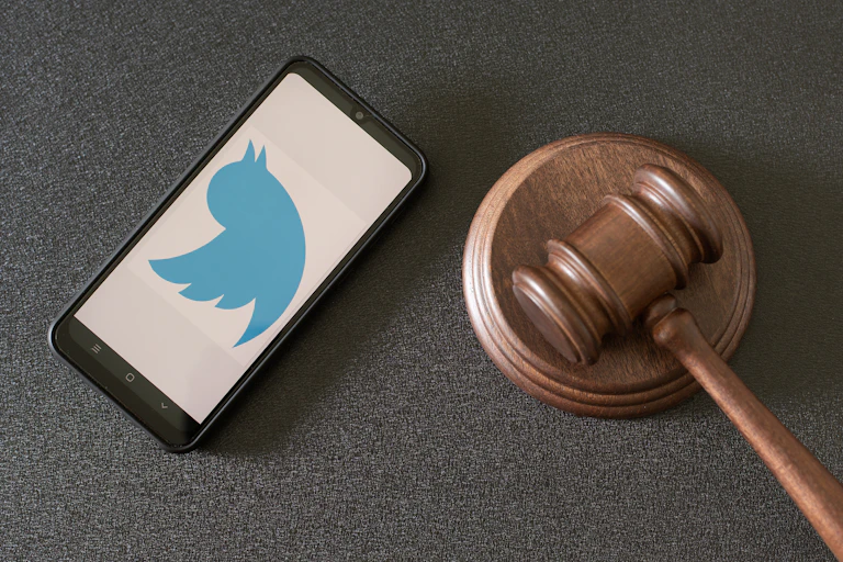 A phone showing the Twitter logo next to a judge's hammer