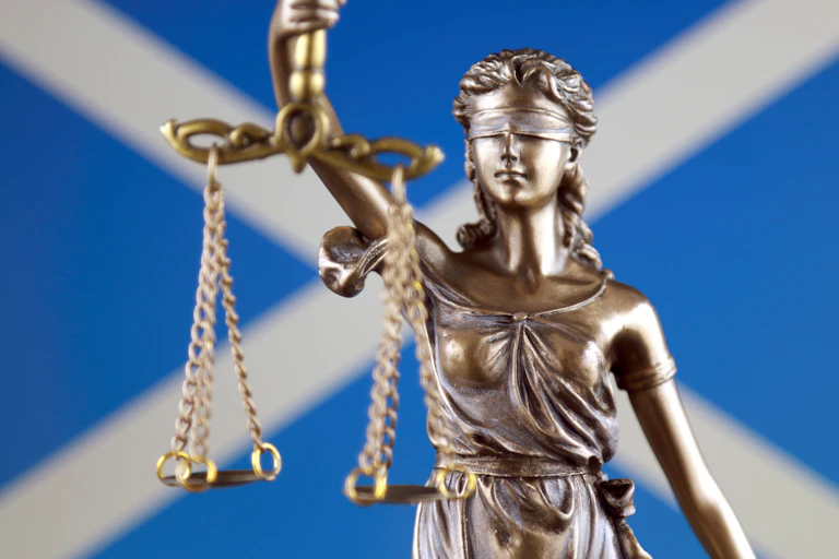Image of the scales of justice against the Saltire flag.