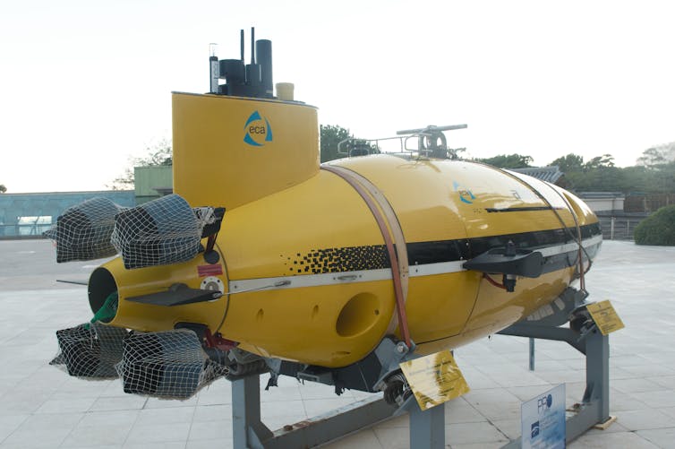 A yellow submarine vehicle is mounted on a stand on land