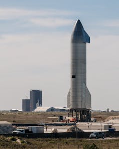 A silver rocket standing on a pad.