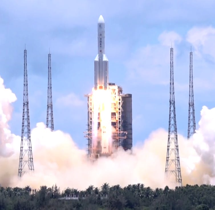 A white rocket lifting off in a cloud of smoke and fire.