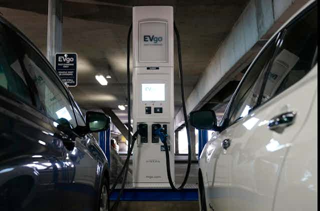 Two electric cars charging in a train station garage.