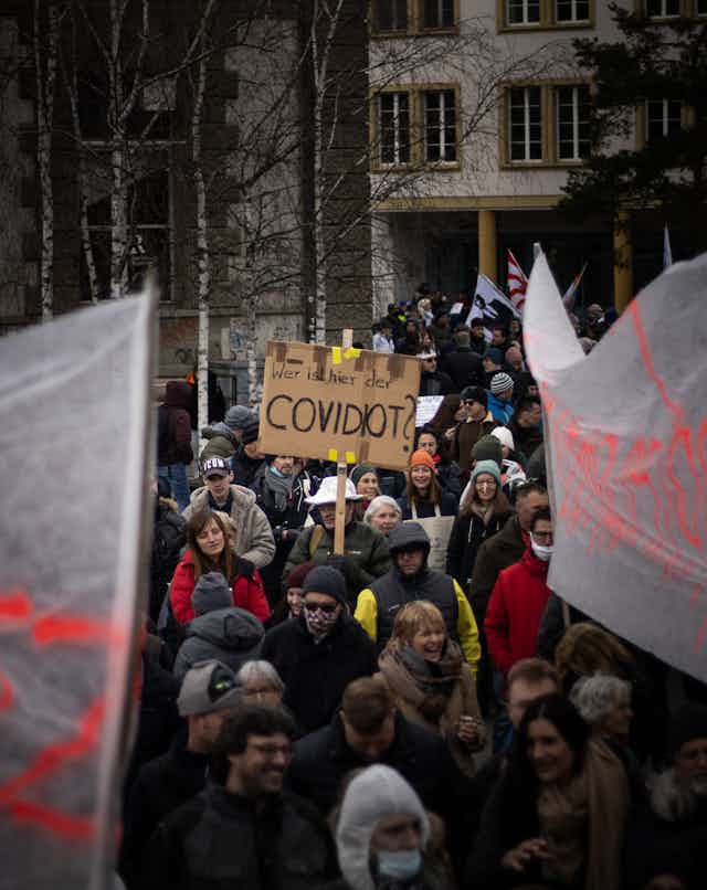 Man holds sign saying 'COVIDIOT'