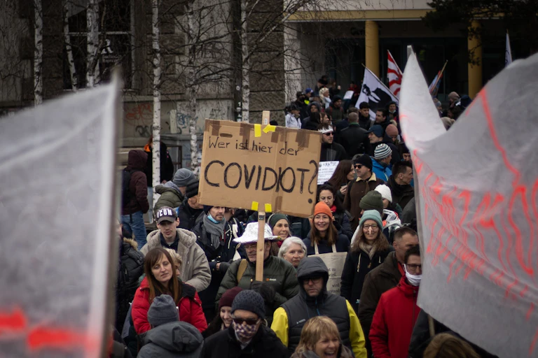 Man holds sign saying 'COVIDIOT'