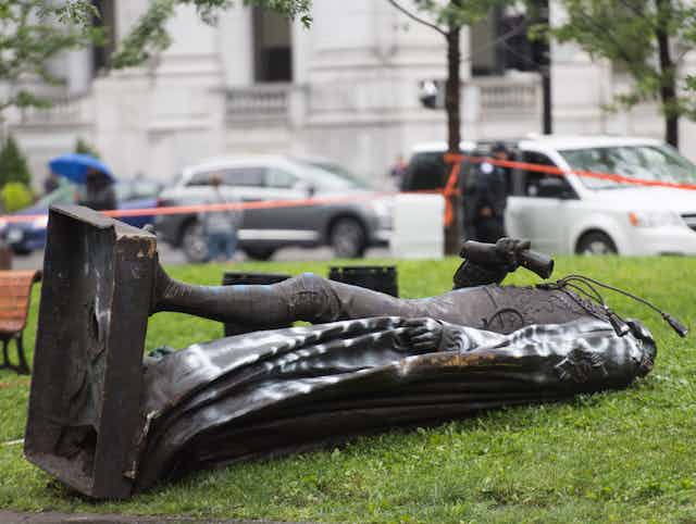 A toppled statue lies on grass