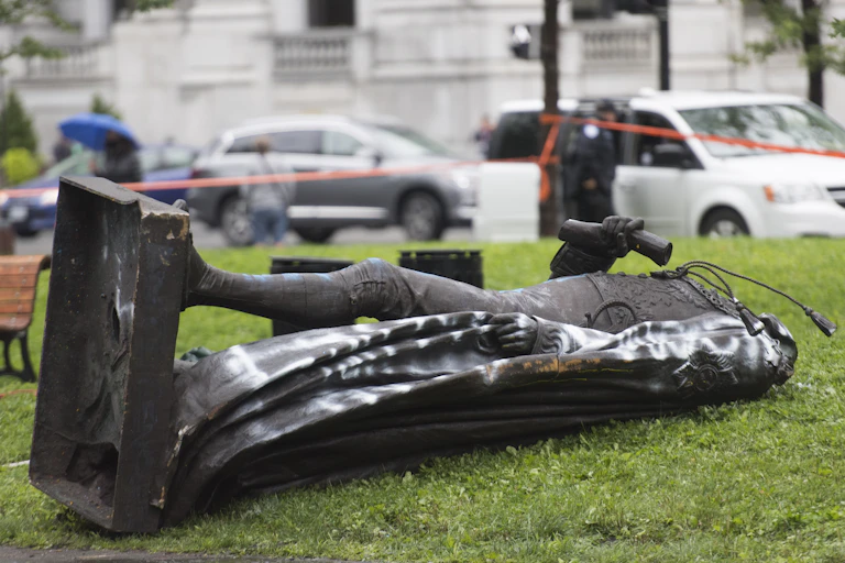 A toppled statue lies on grass