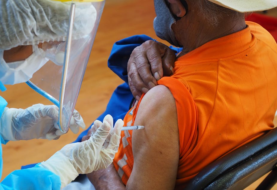 A nurse gives a COVID-19 shot in a man's arm.
