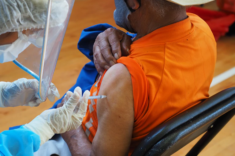 A nurse gives a COVID-19 shot in a man's arm.