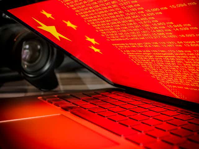 A laptop screen showing the Chinese flag and lines of code