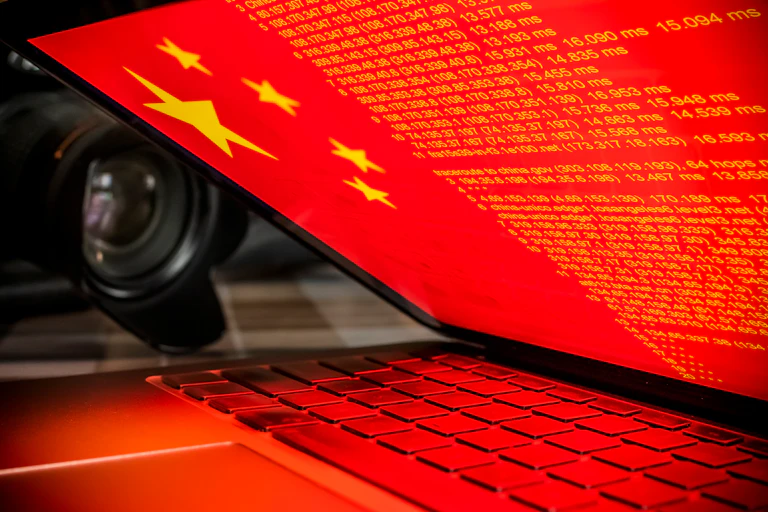 A laptop screen showing the Chinese flag and lines of code