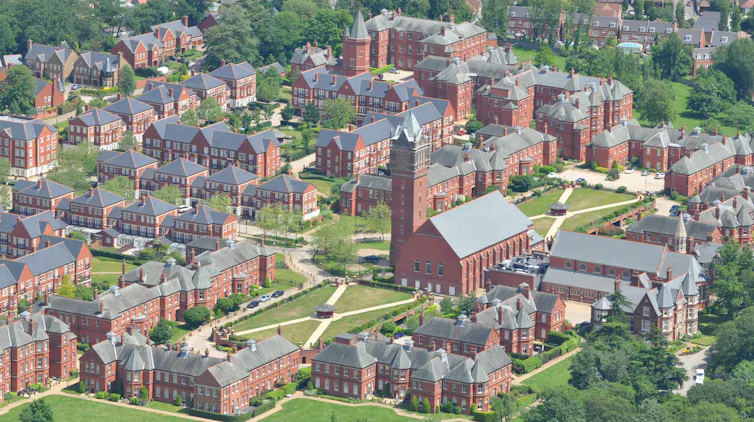 Red and grey buildings are dotted around a grassy area