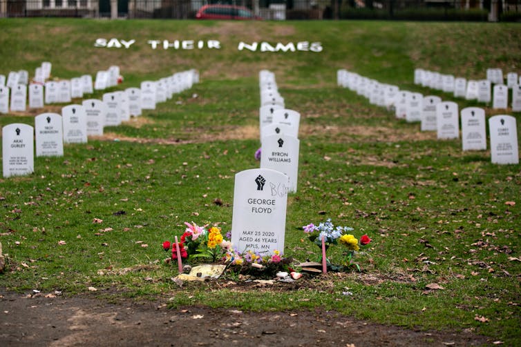 George Floyd's headstone sits front and center in an orderly faux cemetery with other white headstones set up in grass