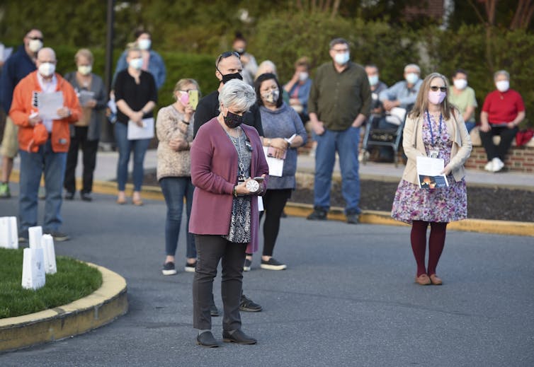 masked people stand outside in a socially distanced way