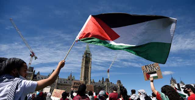 A protester waves the Palestinian flag in front of Parliament Hill. 