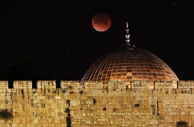 A red moon over an ancient mosque.